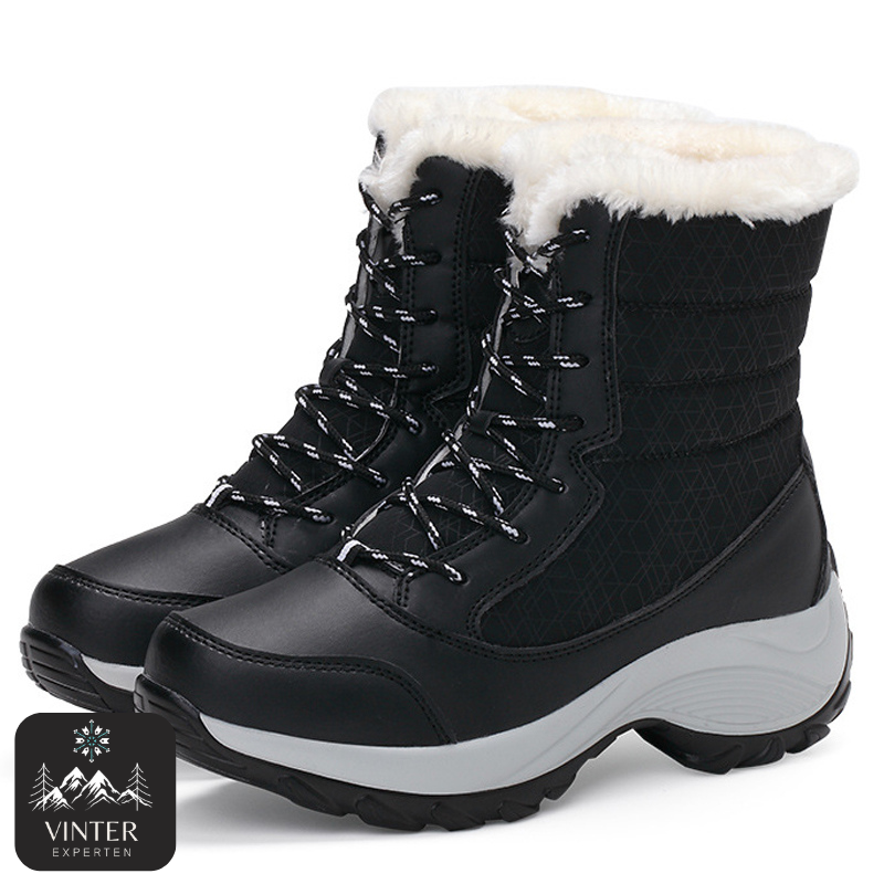 Svarta vinterkängor för dam från Vinterexperten, med vit värmande fuskpäls, snörning och robust halkfri sula för komfort och stabilitet under kalla vinterdagar.