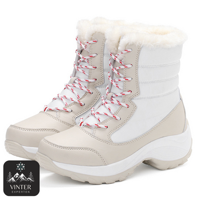 Vita vinterkängor för dam från Vinterexperten, med vit värmande fuskpäls, snörning och robust halkfri sula för komfort och stabilitet under kalla vinterdagar.
